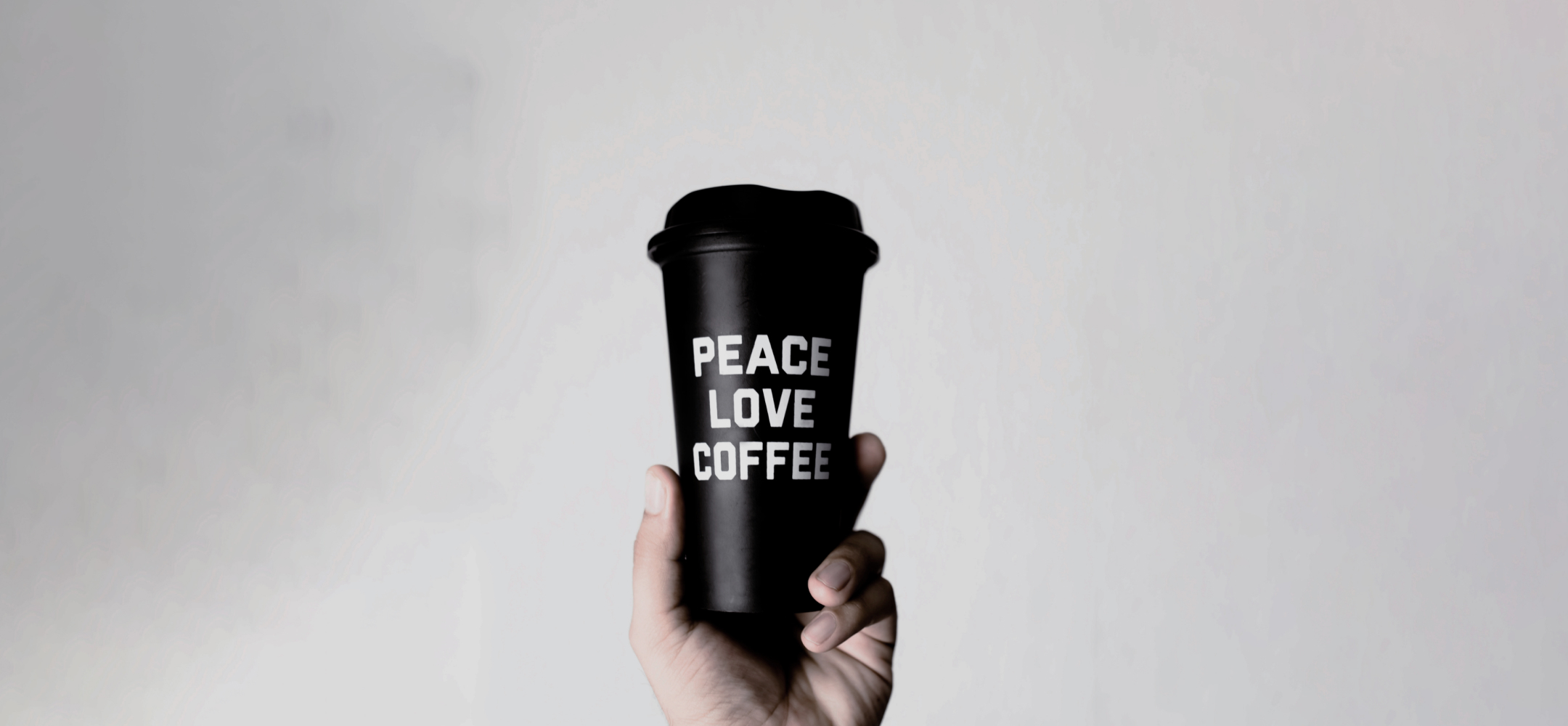 peace love coffeeとかかれたコーヒーカップのを持つ手